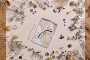 Creative flatlay featuring dried flowers, a notepad, and eyeglasses for an artistic vibe.